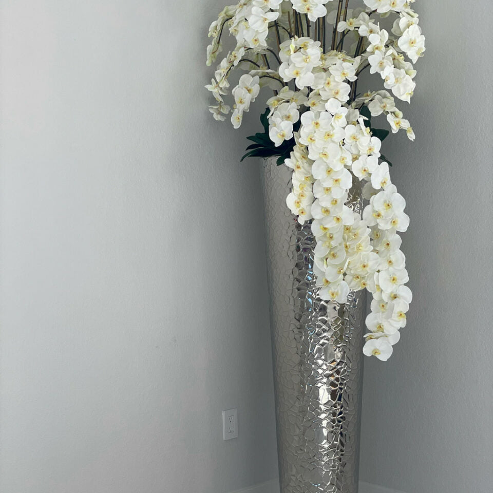 Cascading Phalaenopsis Orchids in an extra-tall vase with a hammered finish.