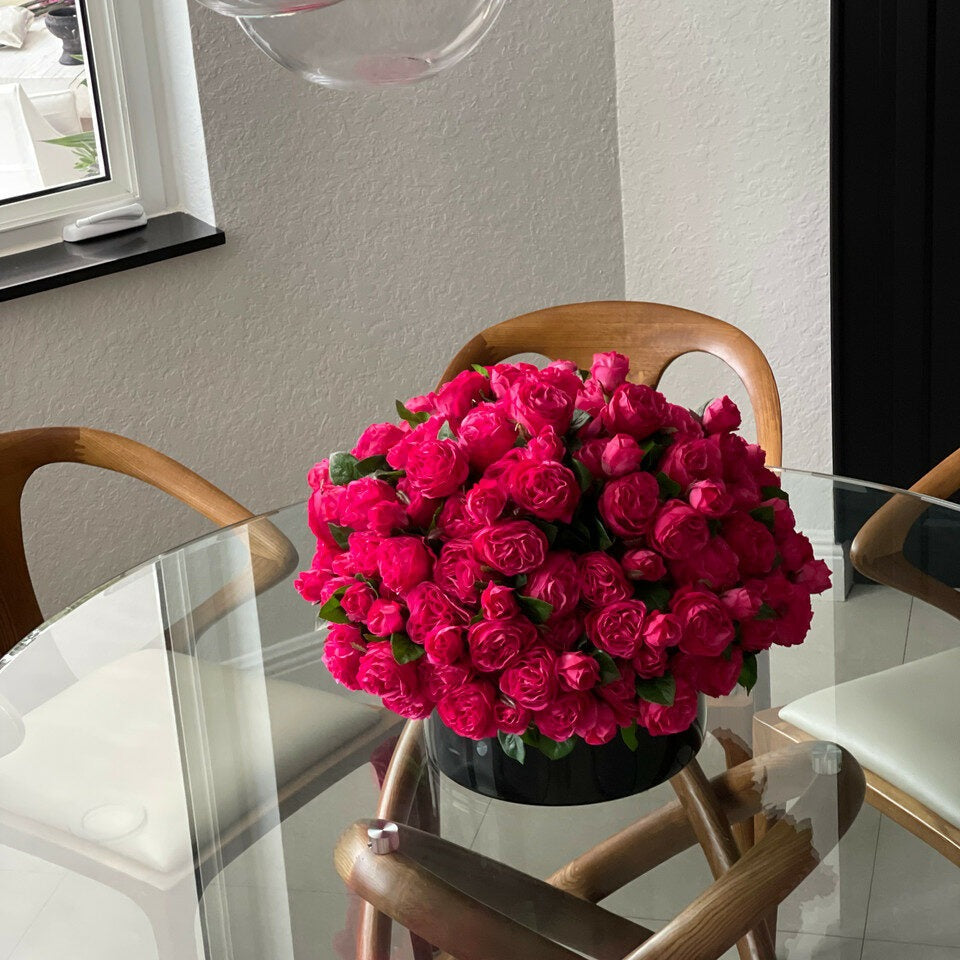 Dark pink English roses in a black glass vase.