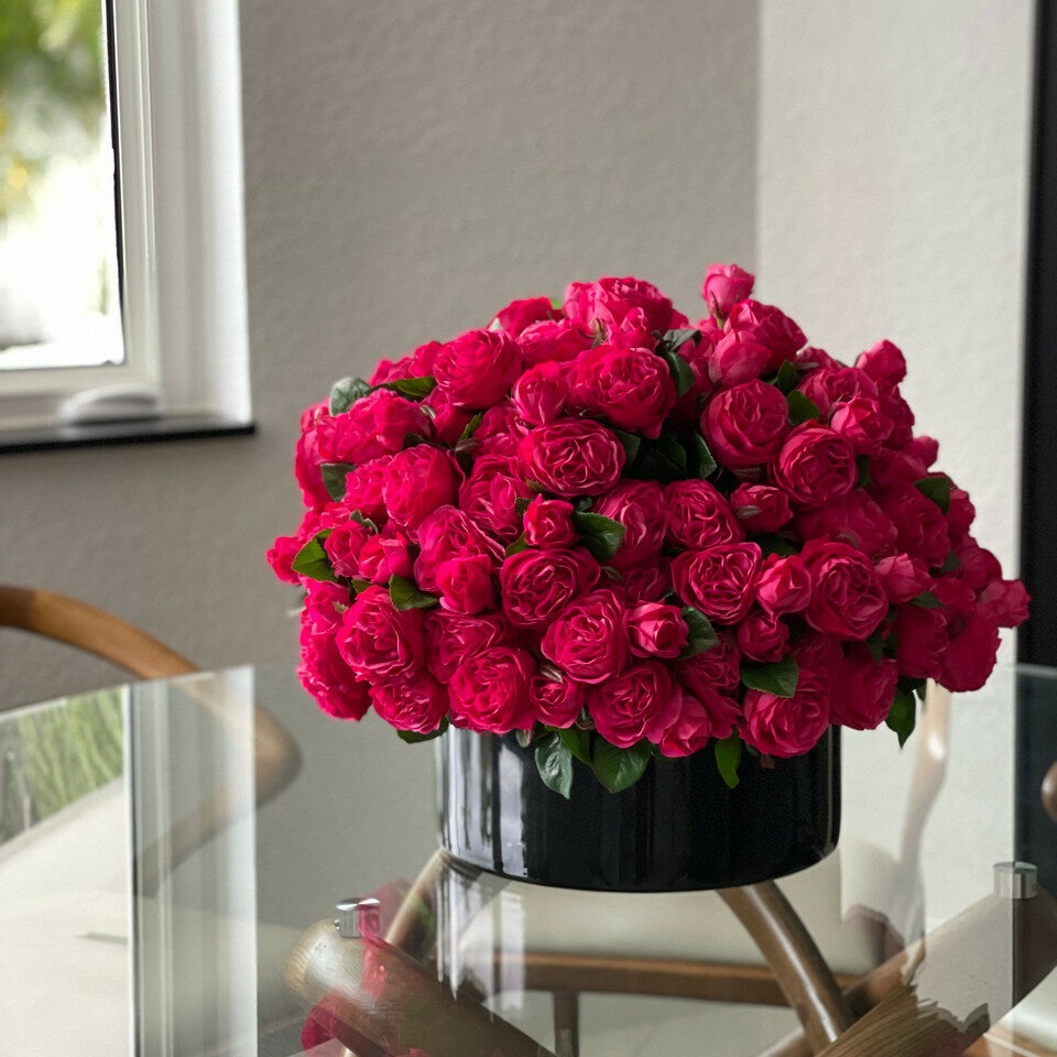 Dark pink English roses in a black glass vase.