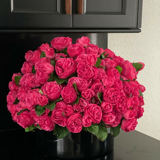 Dark pink English roses in a black glass vase.