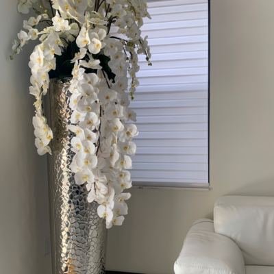 Cascading Phalaenopsis Orchids in an extra-tall vase with a hammered finish.